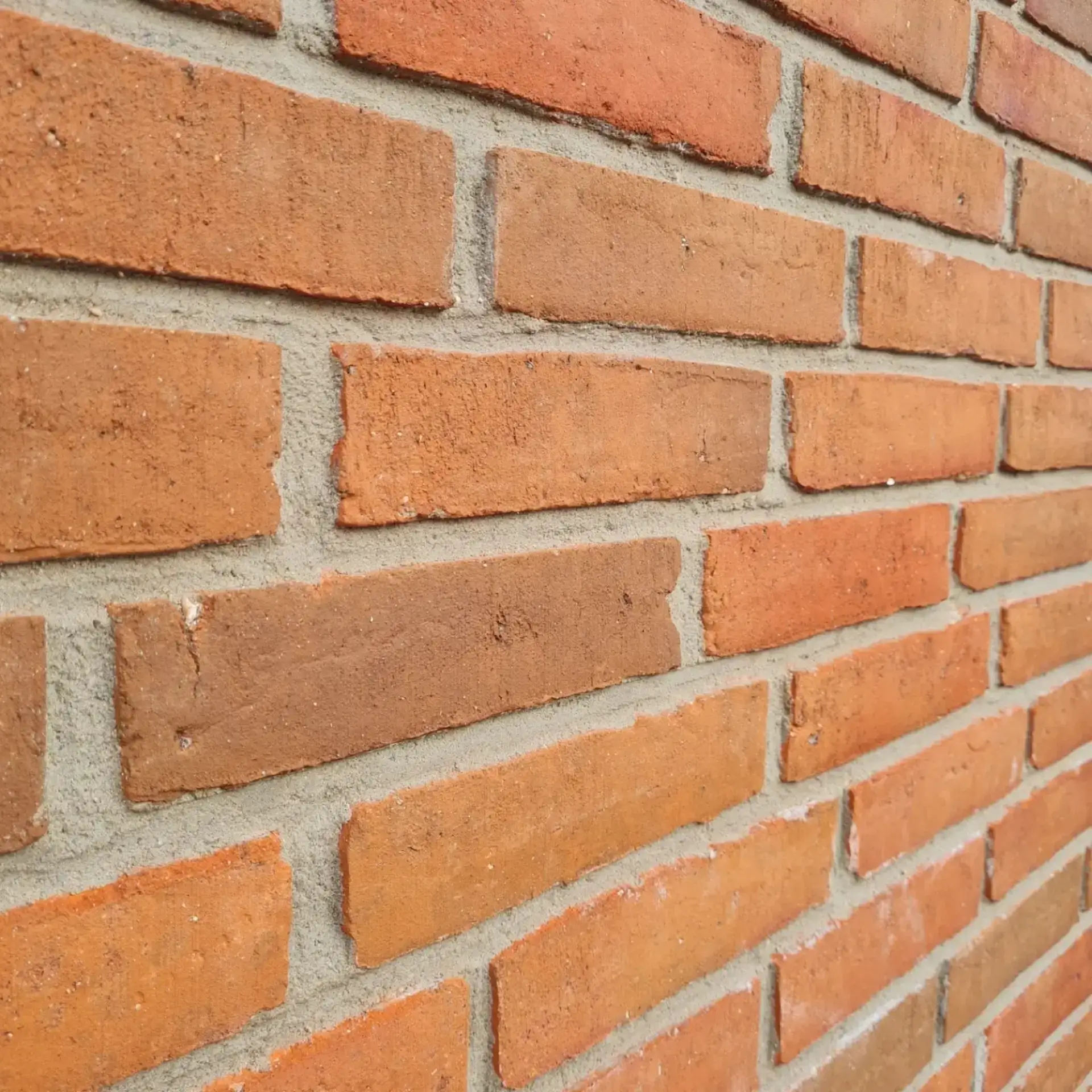 Nærbillede af en murstensvæg med røde teglsten og grå mørtel.